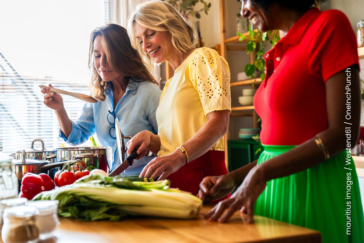 
Drei Frauen bereiten in der Küche ein gesundes Essen vor.
